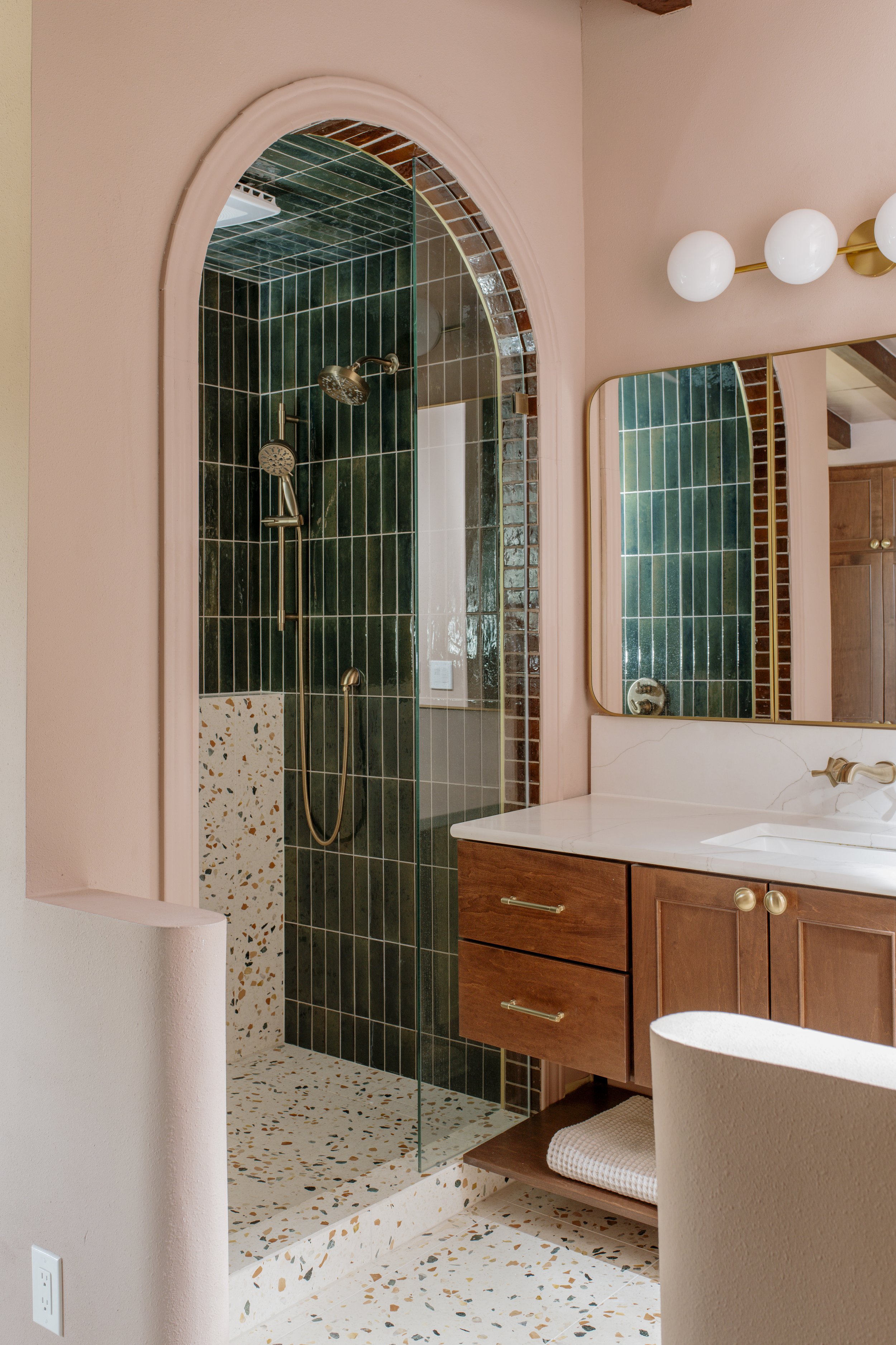 The arched tile shower is one of the best details in this project and is paired with the curved ends of the pony walls dividing the bathroom and the closet area
