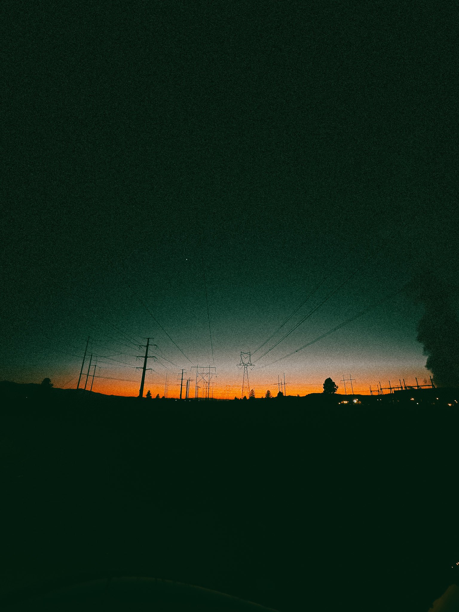 Silhouette of power lines during sunset with an orange and blue sky