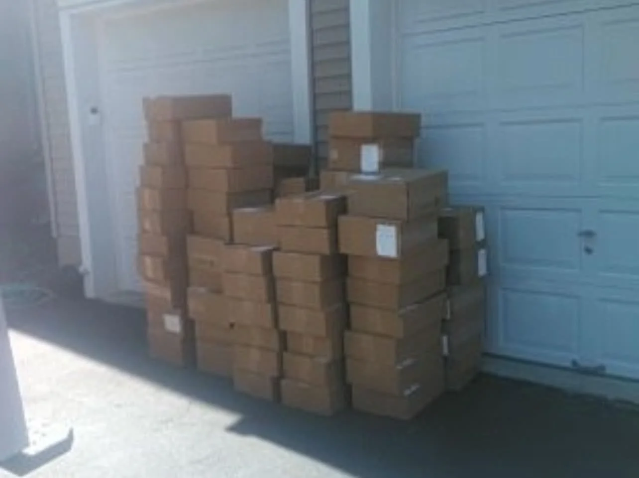 Stacks of cardboard boxes outdoors next to a garage door.