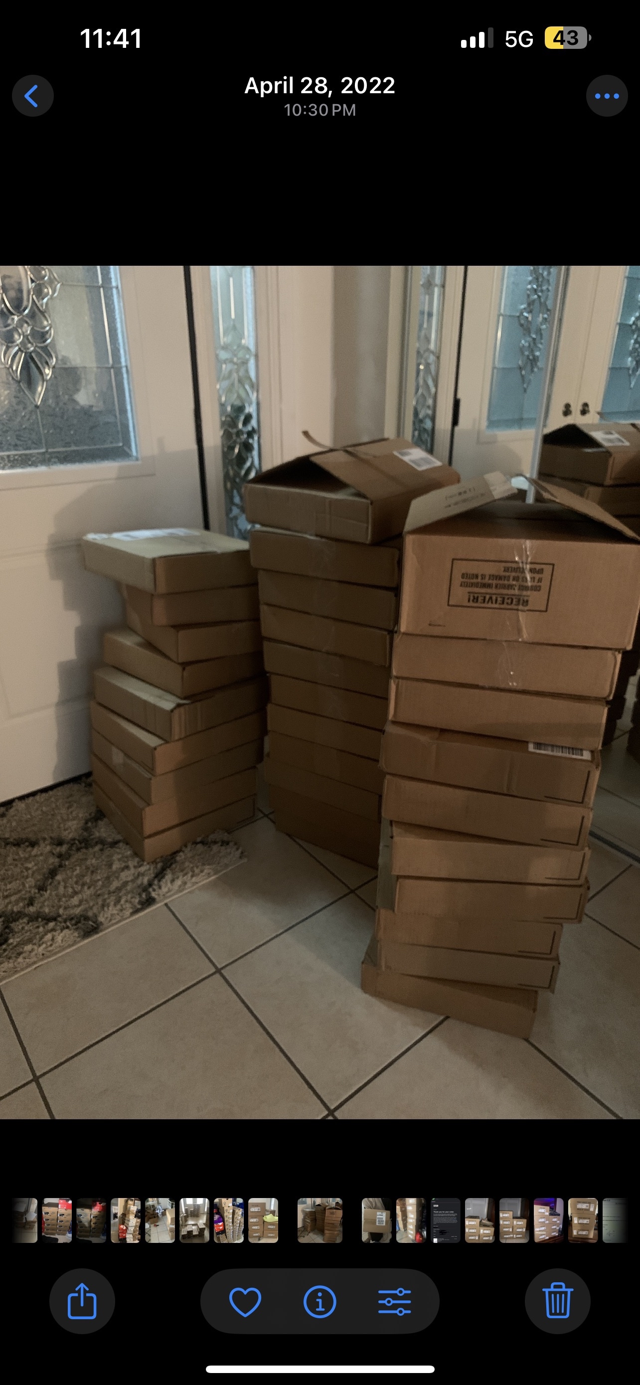 Stack of cardboard boxes arranged in multiple columns indoors near a door with decorative glass panels.