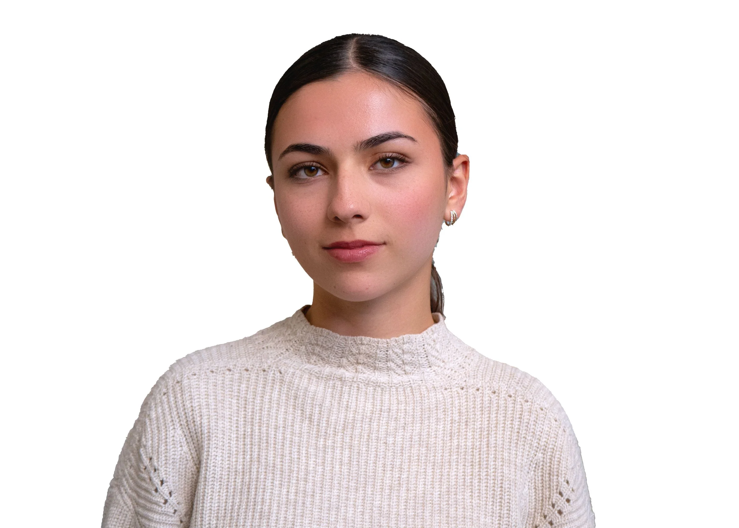 A young man with curly brown hair, light skin, wearing a dark grey suit, white shirt, and a patterned blue tie, standing in front of a modern building with large glass windows.
