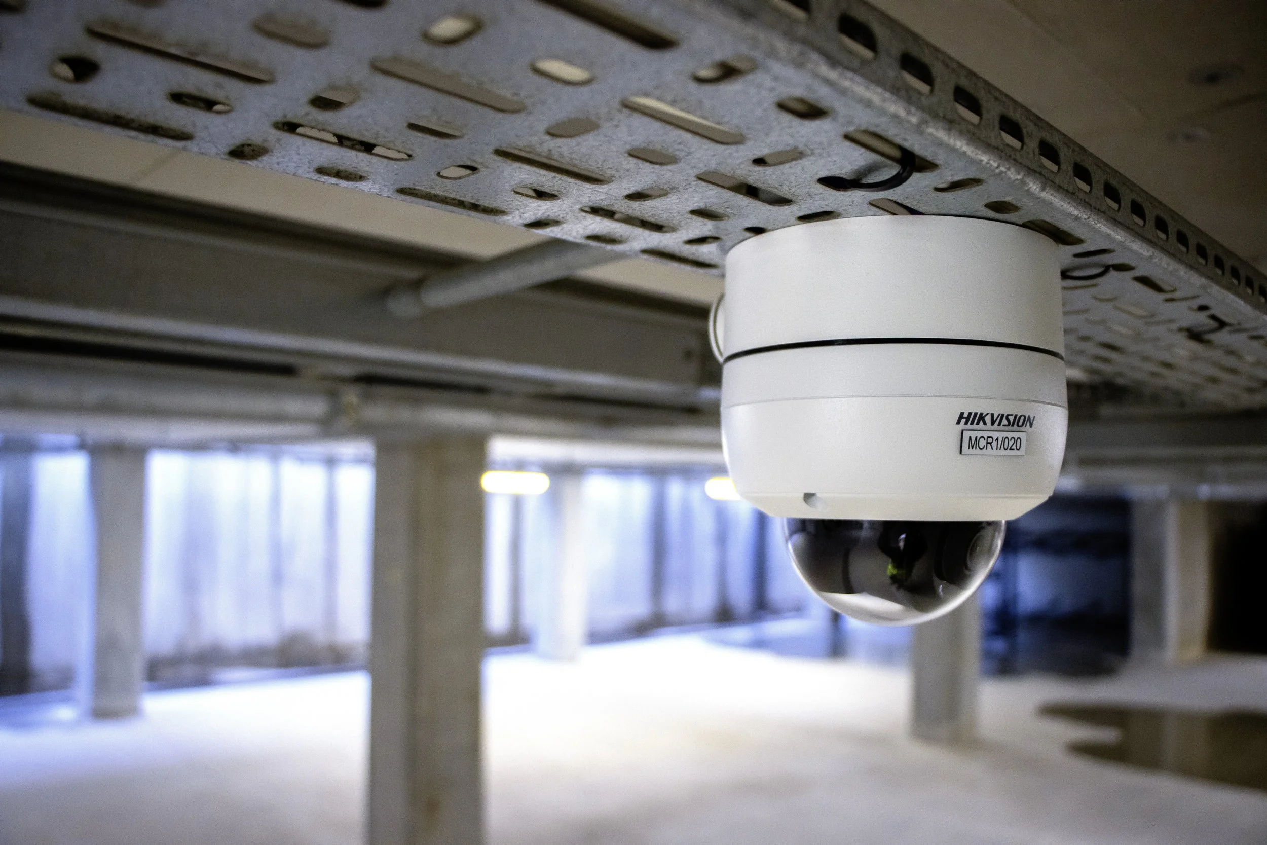 Line of parked cars outside a building with reflective windows and autumn foliage reflected in the glass.