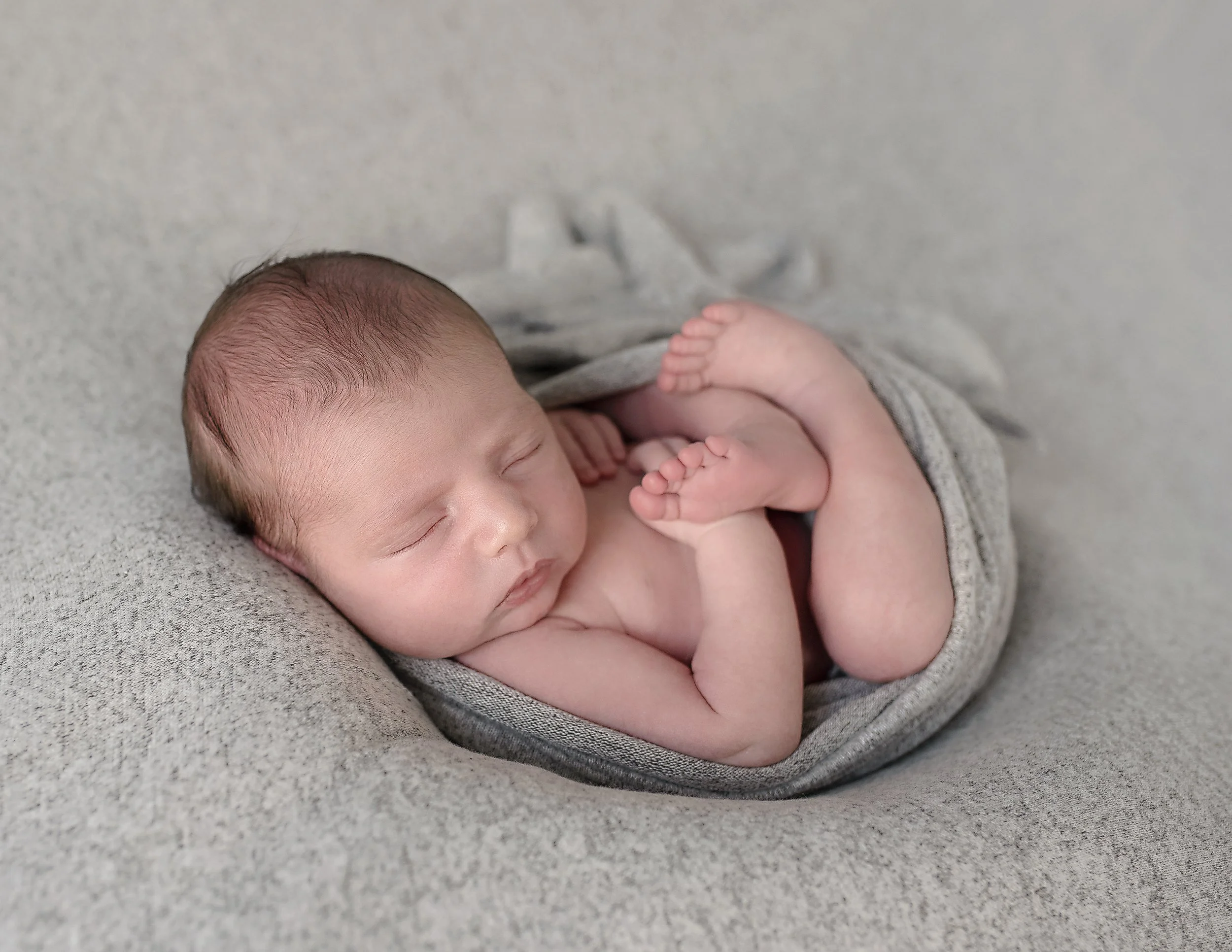 Newborn baby wrapped in neutral swaddle during studio session in Rhode Island