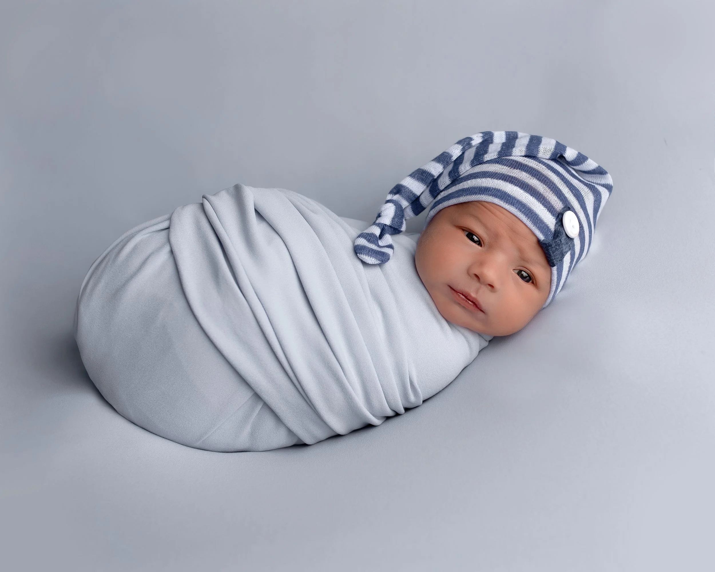 Rhode Island newborn photography swaddled baby boy wearing a sleepy cap in studio by Anna Kay Photography
