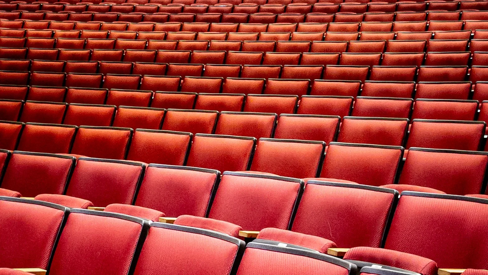 Empty red theater seats arranged in rows.