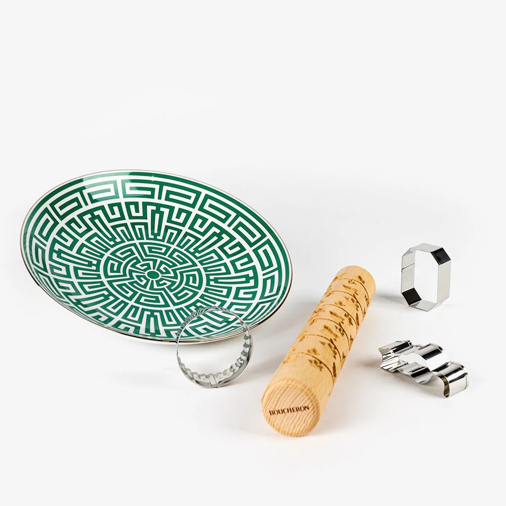 Plateau décoratif avec motif géométrique, bouchon en bois, deux bagues en métal, et un bijou en métal argenté