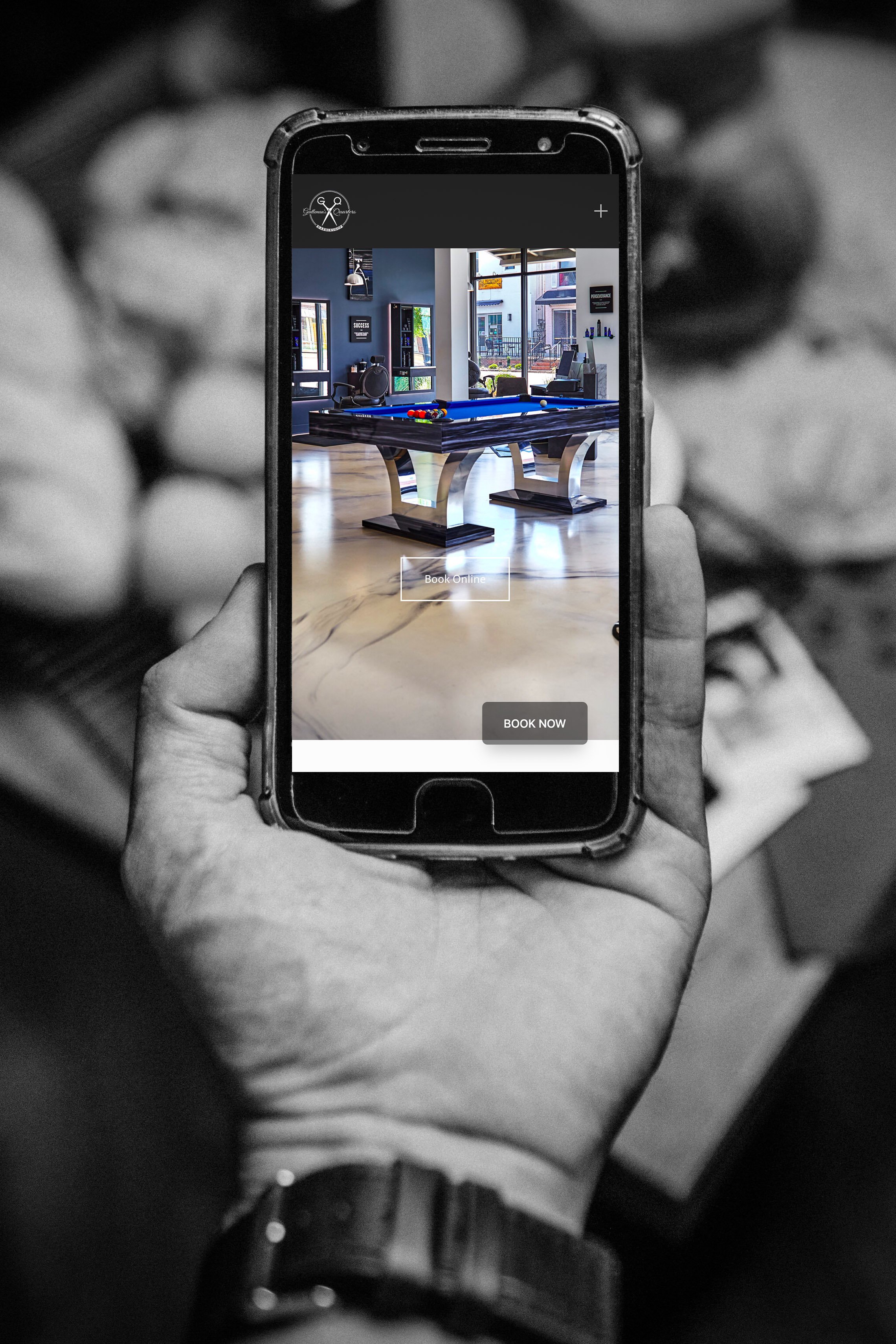 Gentleman's Quarters Barbershop website showing on a cell phone in a man's hand