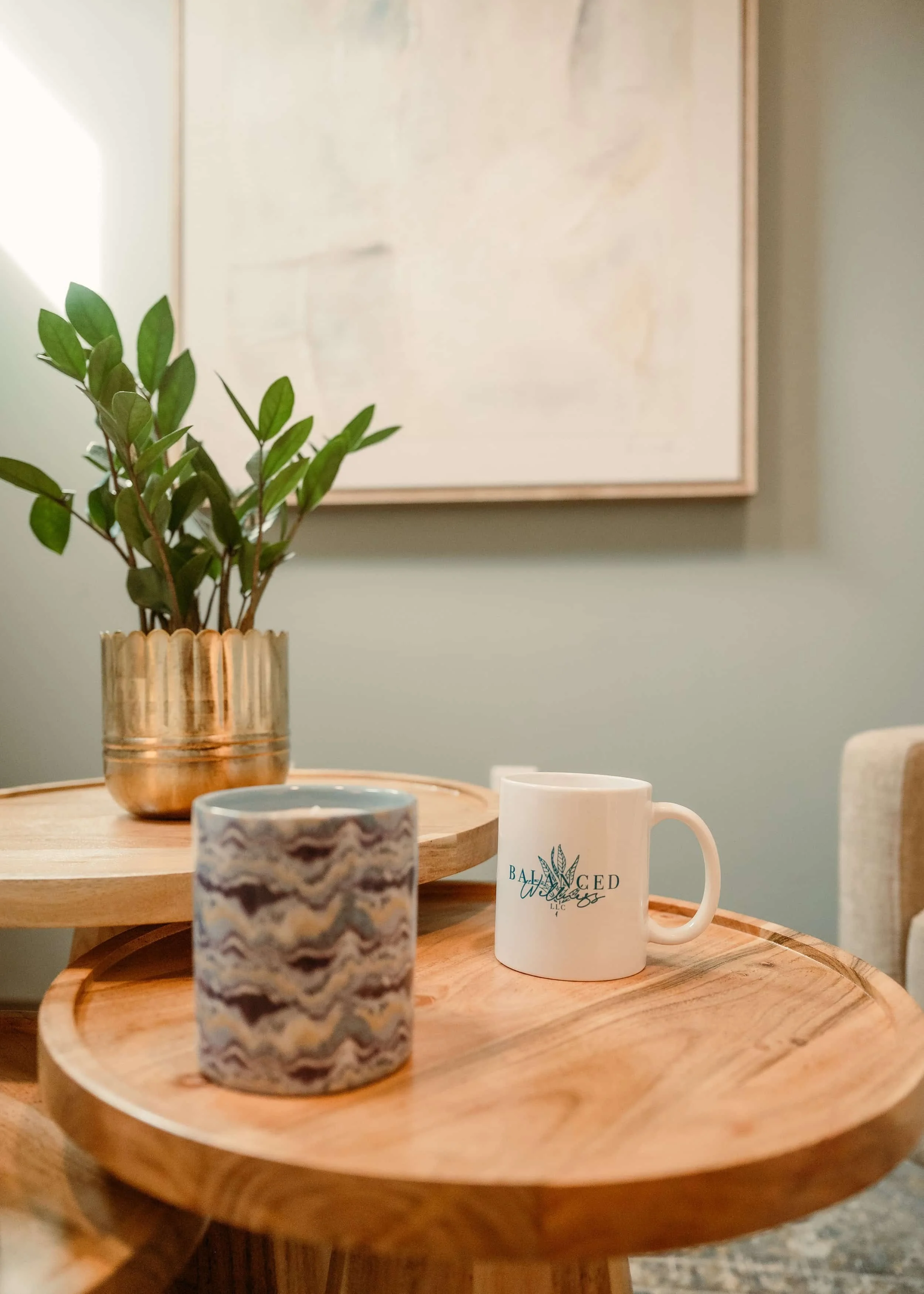 Two side tables displaying a plant, a candle and a balanced wellness mug.