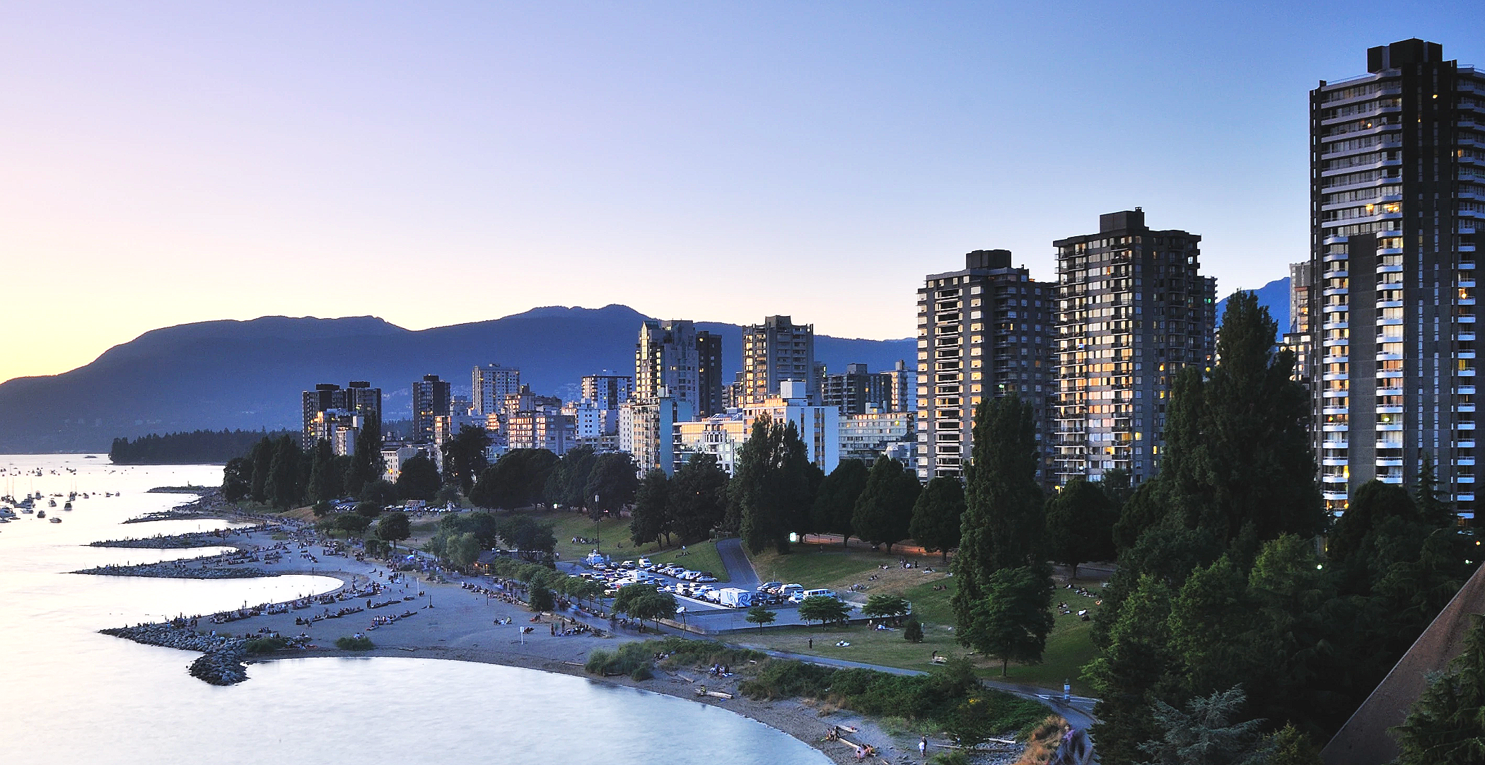 West End Vancouver luxury high-rise condominiums and penthouses overlooking English Bay Beach at sunset with North Shore mountains, showcasing premium oceanfront living and million-dollar views in downtown Vancouver's most prestigious waterfront neig