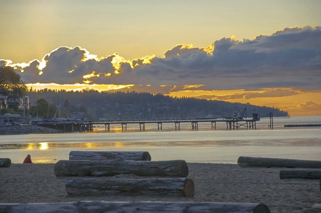 Kitsilano Beach Vancouver sunrise with golden hour light reflecting off English Bay waters, luxury waterfront condominiums and yacht marina showcasing premium beachfront lifestyle and million-dollar oceanfront living