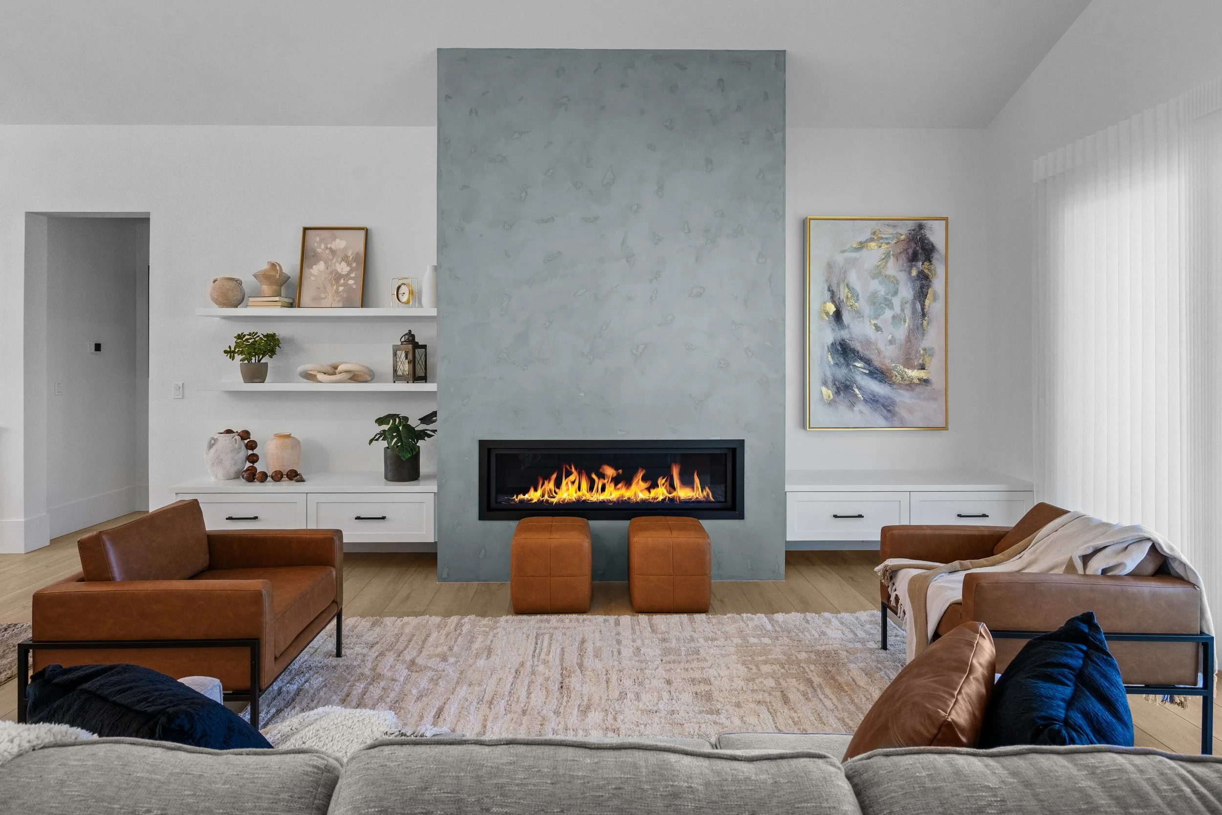 A modern living room with a fireplace and decorative items on white shelves.