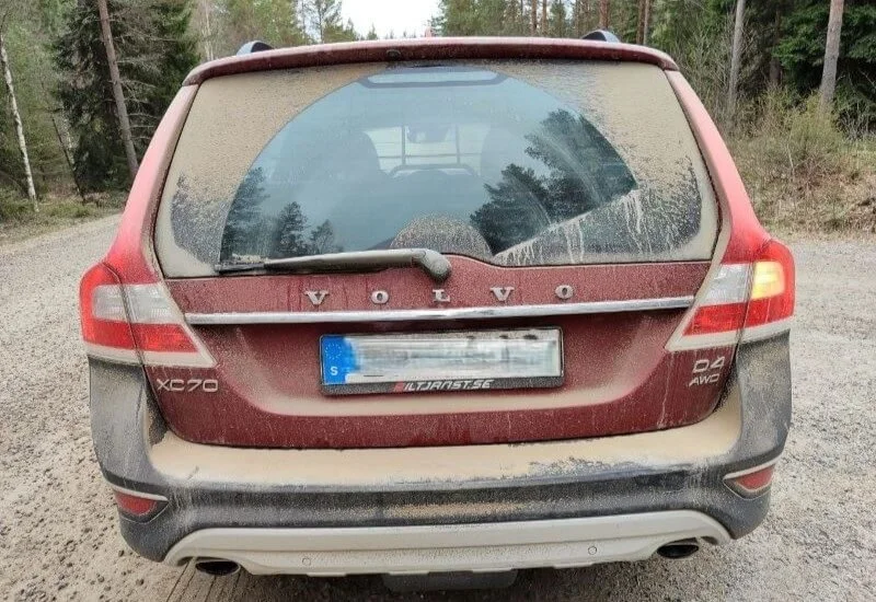 Hinteransicht eines zugestaubten Volvos auf einer Schotterstraße