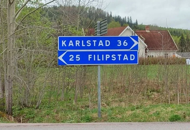 Zwei Wegweiser zu schwedischen Städten am Straßenrand