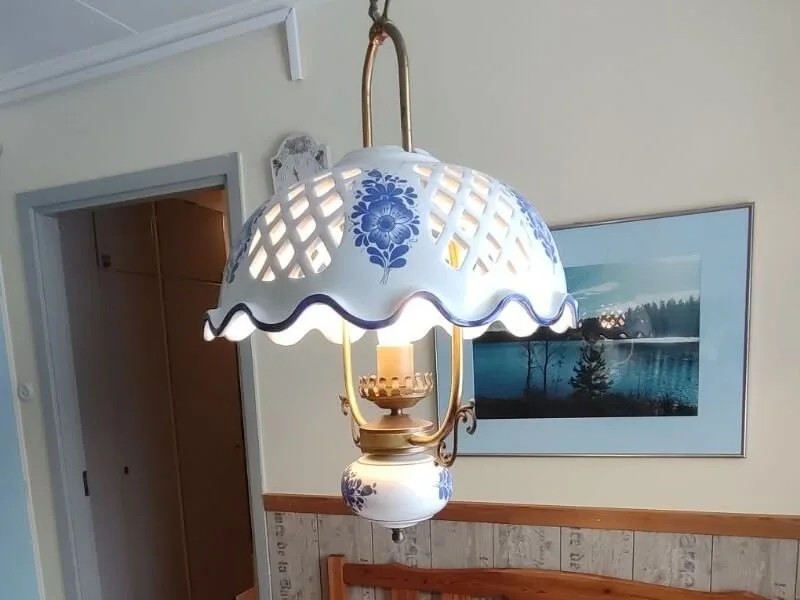 Hängeleuchte mit blauer Blumenmuster und weißem Schirm in einem Raum, neben einem Bild an der Wand
