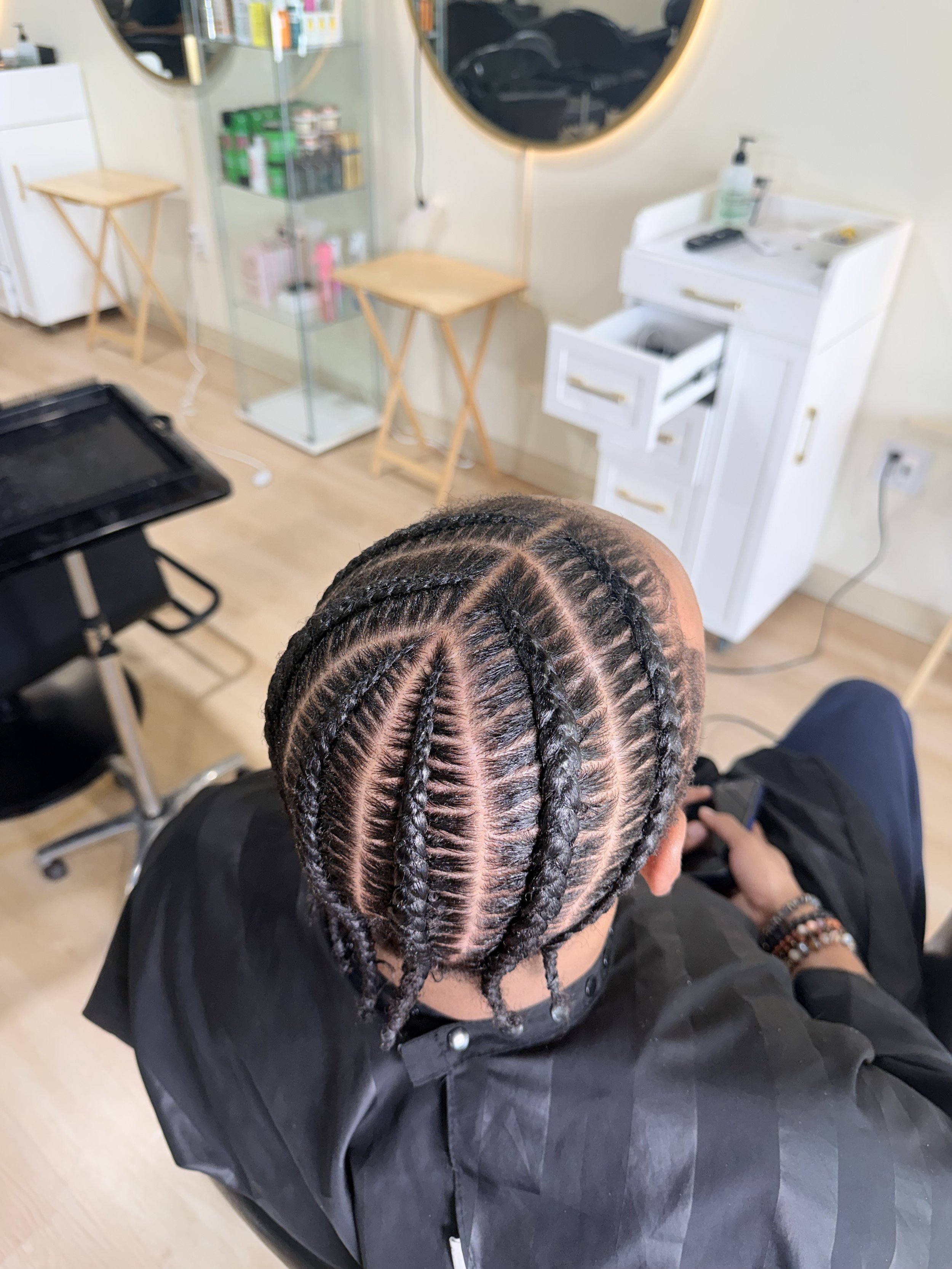Men’s stitch braids with symmetrical curved parting and a polished finish