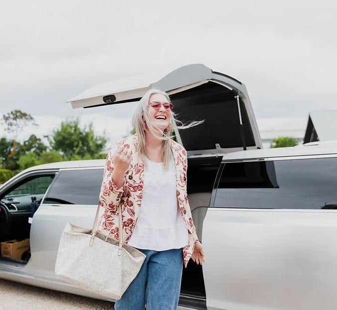 Kate Astill stepping out of a limousine with a wide smile carrying a handbag