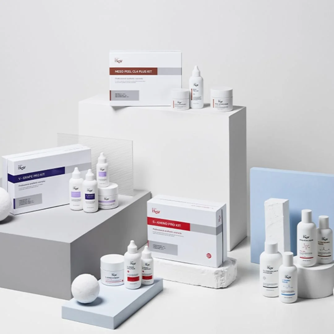 Assorted skincare products displayed on white and gray platforms with minimalistic background.
