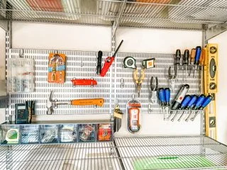 An ELFA metal pegboard holding tools in a garage