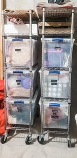 Two metal storage shelves on wheels holding plastic storage bins