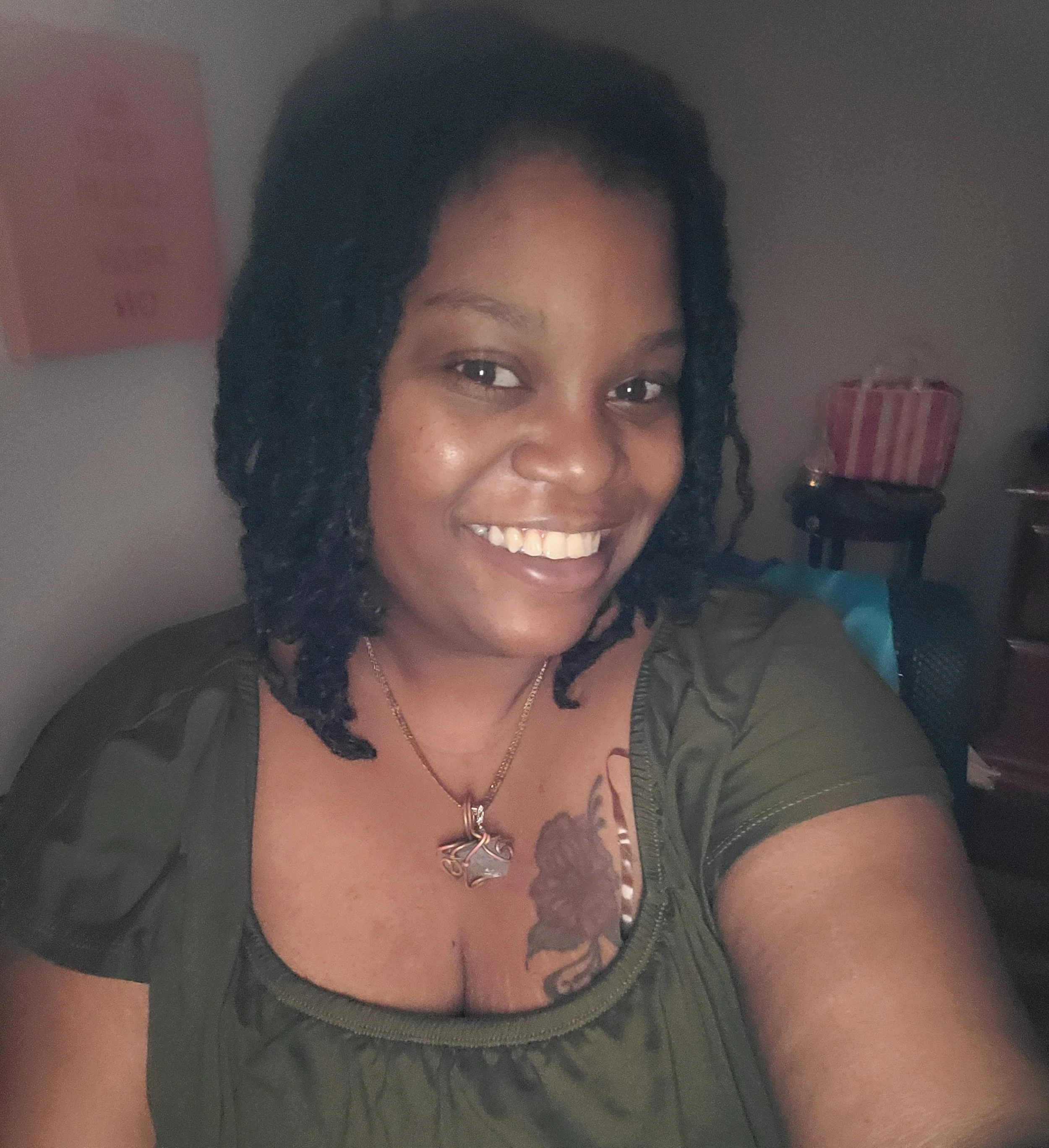 A Black woman with locs wearing a green top.