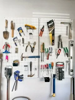 A white pegboard storing hand tools