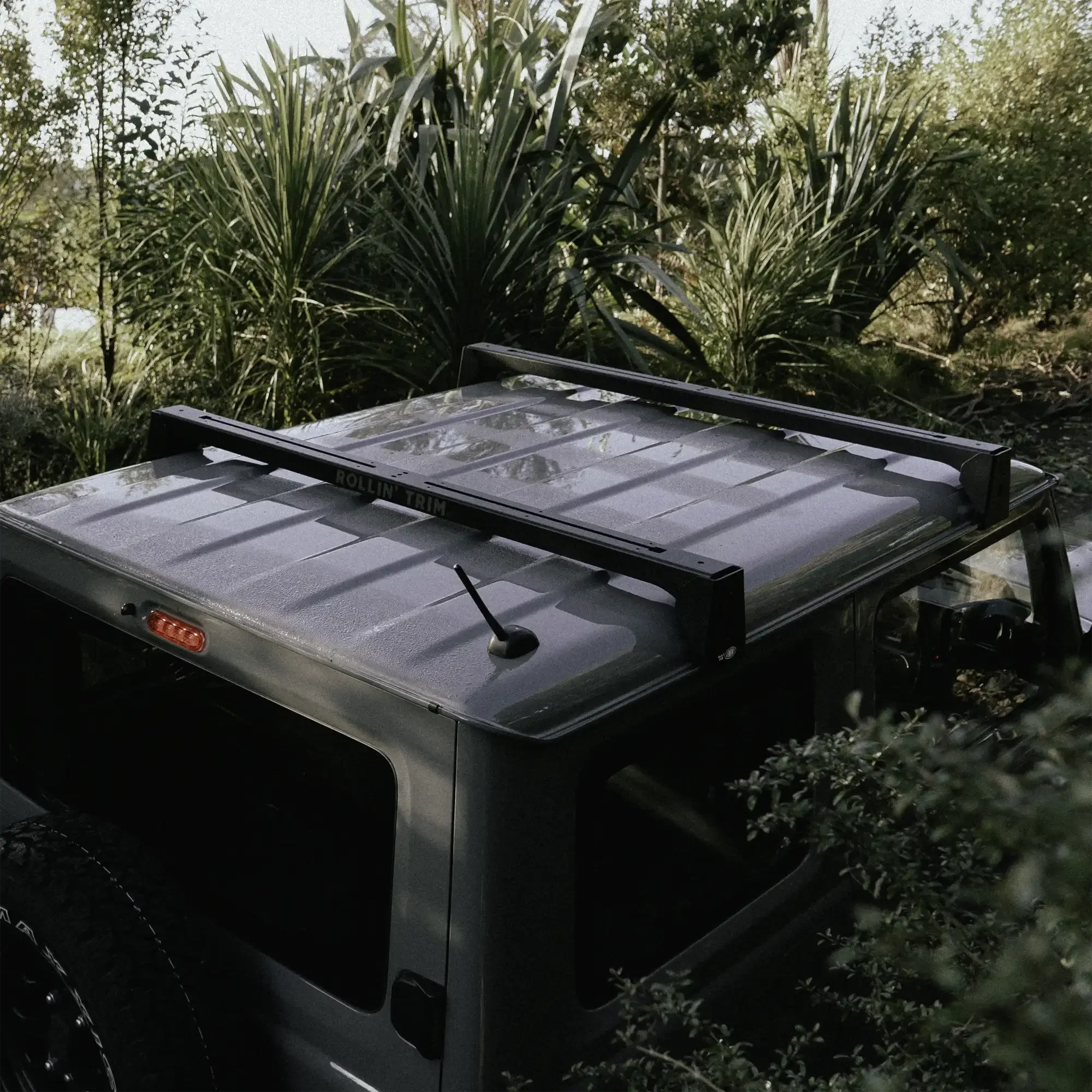 Grey Suzuki Jimny driving through New Zealand bush track, viewed from above.