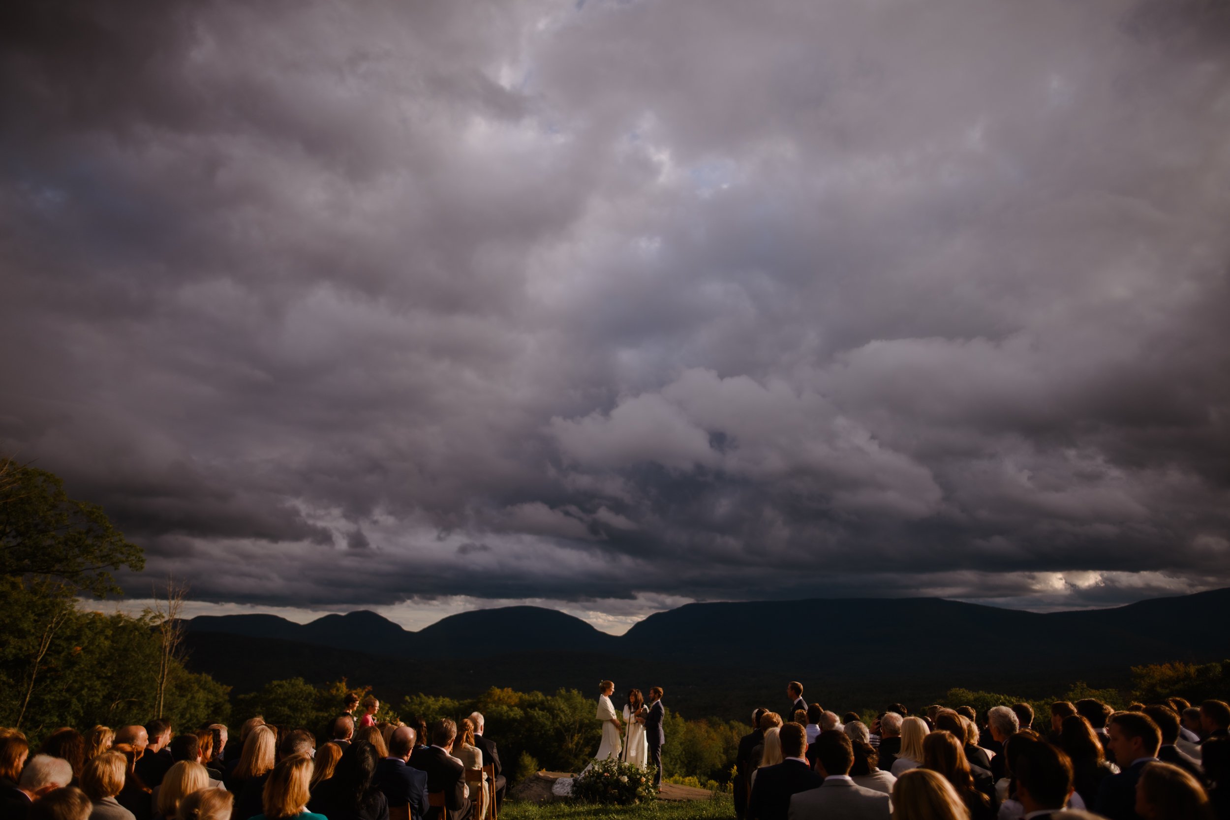 Golden sun shines on wedding ceremony held on a mountain top in the Catskills, NY.