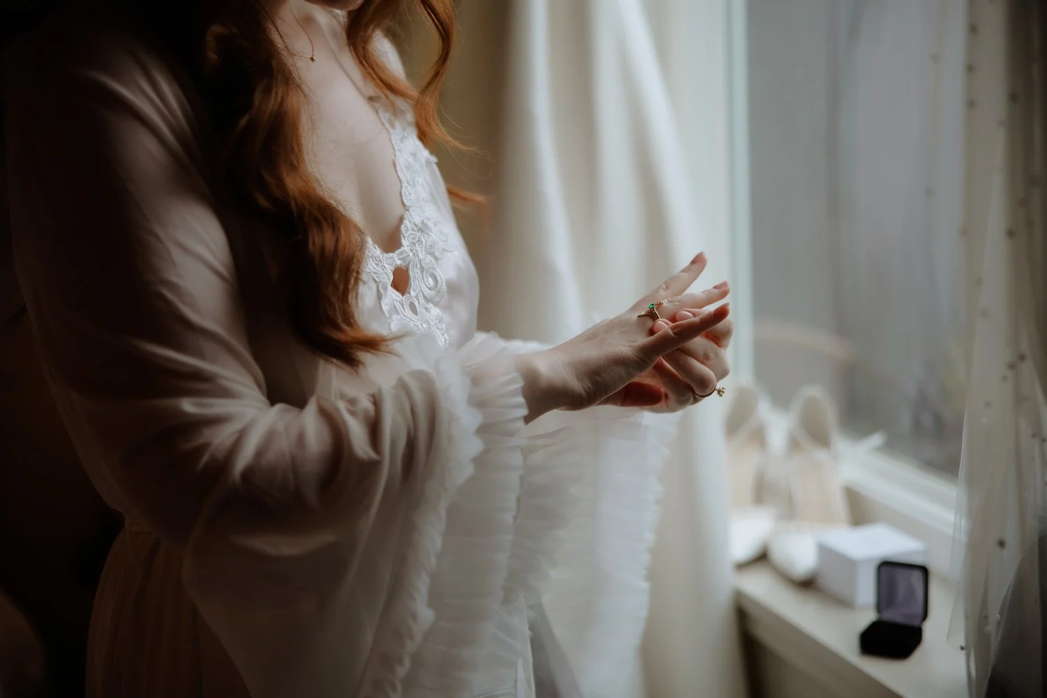 Bride adjusting her rings by a sunlit window while getting ready near Beacon.