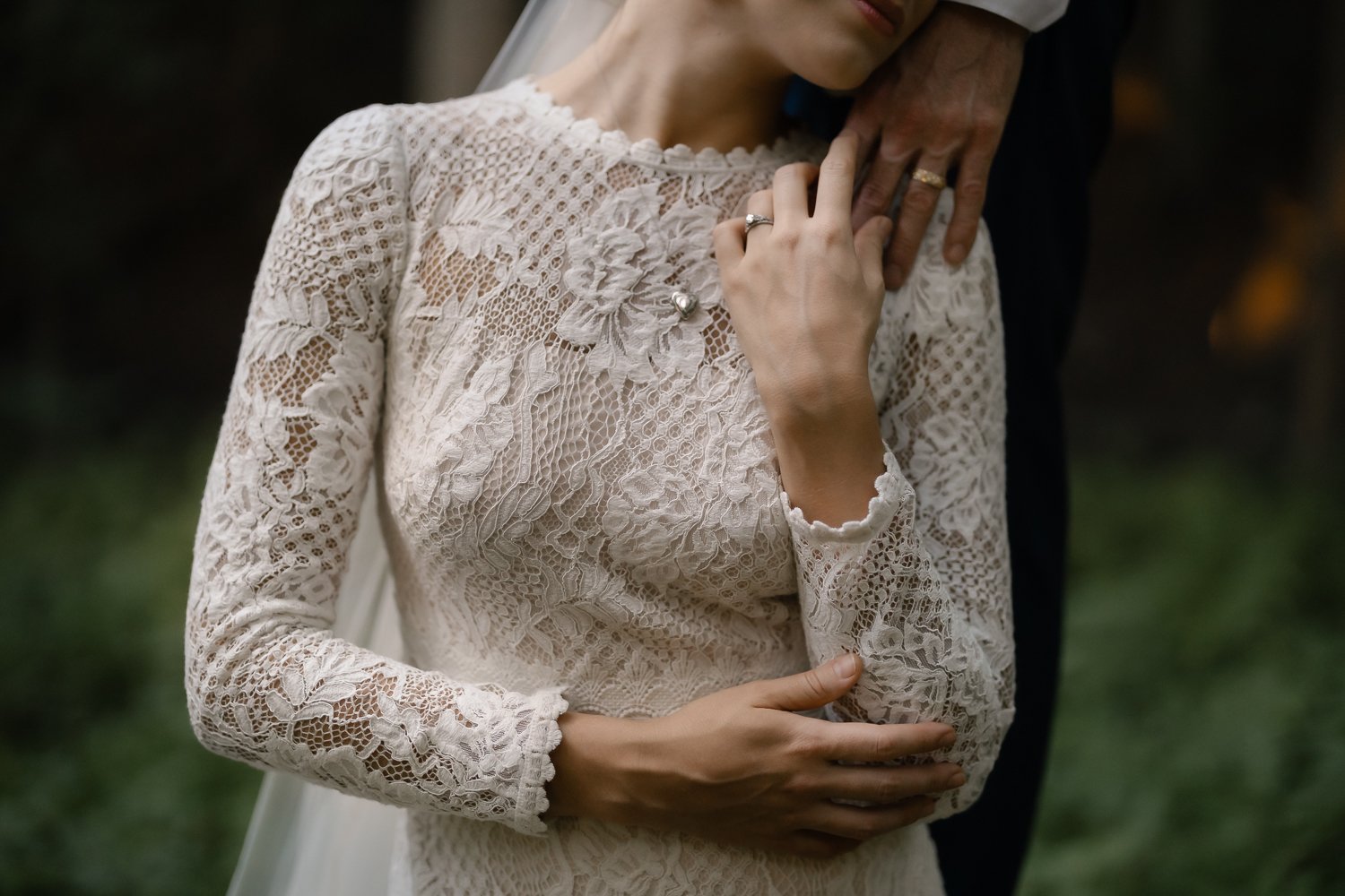 Romantic and intimate portrait of bride gently touching grooms hand on her shoulder.