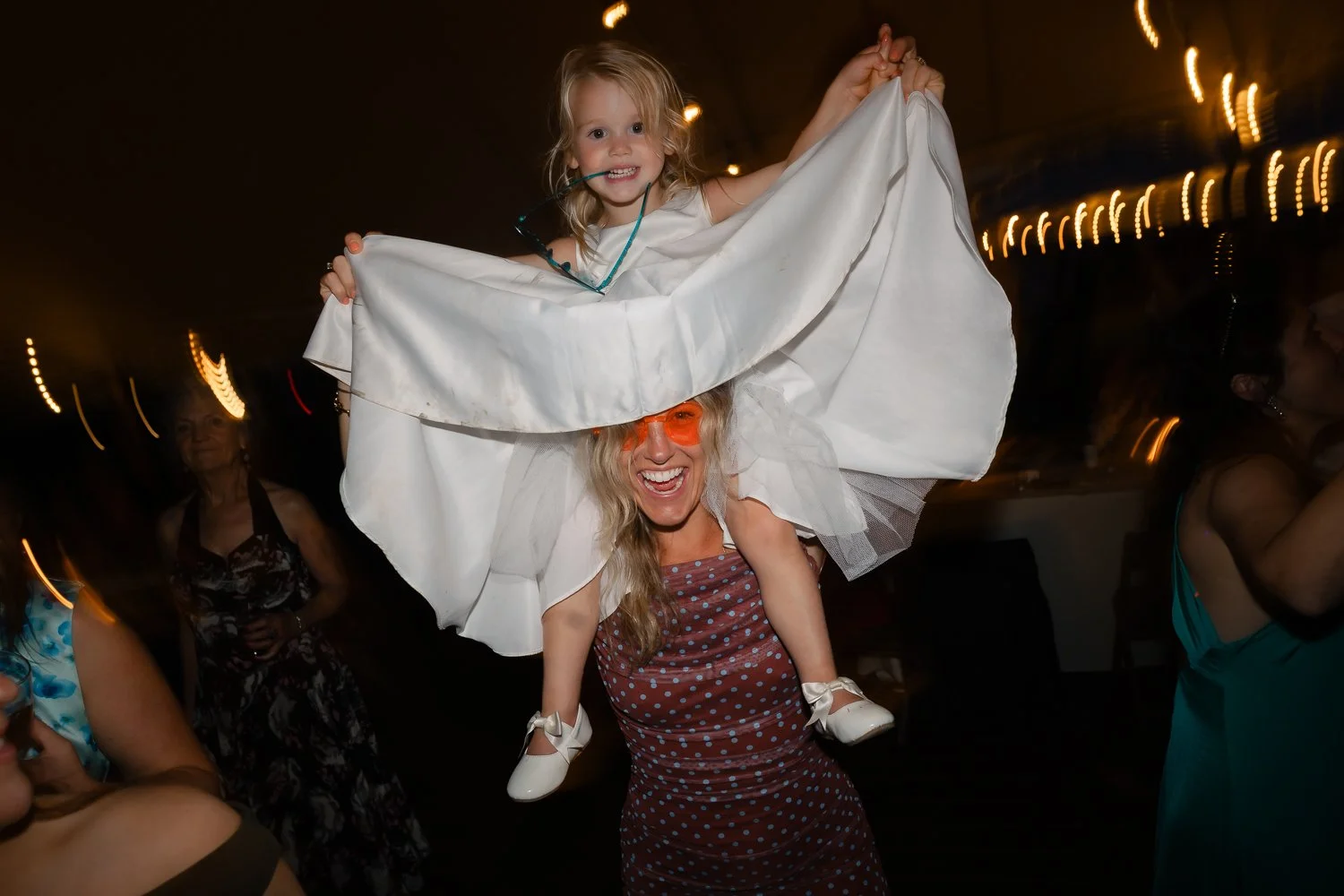 Flowergirl sits on her moms shoulder while dancing at wedding reception in the Catksills.
