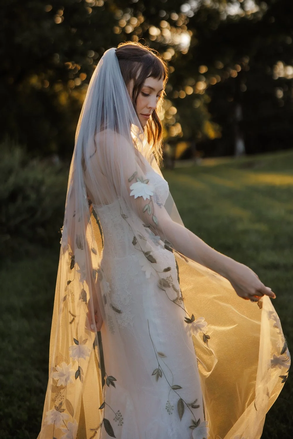 Bride is bathed in golden light as she plays with her veil during Wallkill wedding.