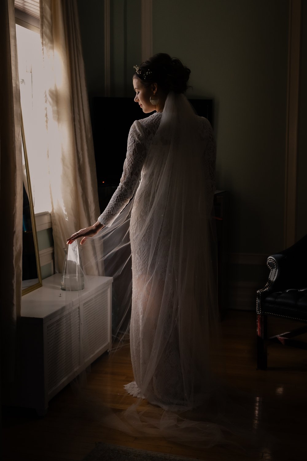 Bride bathed in moody window light.