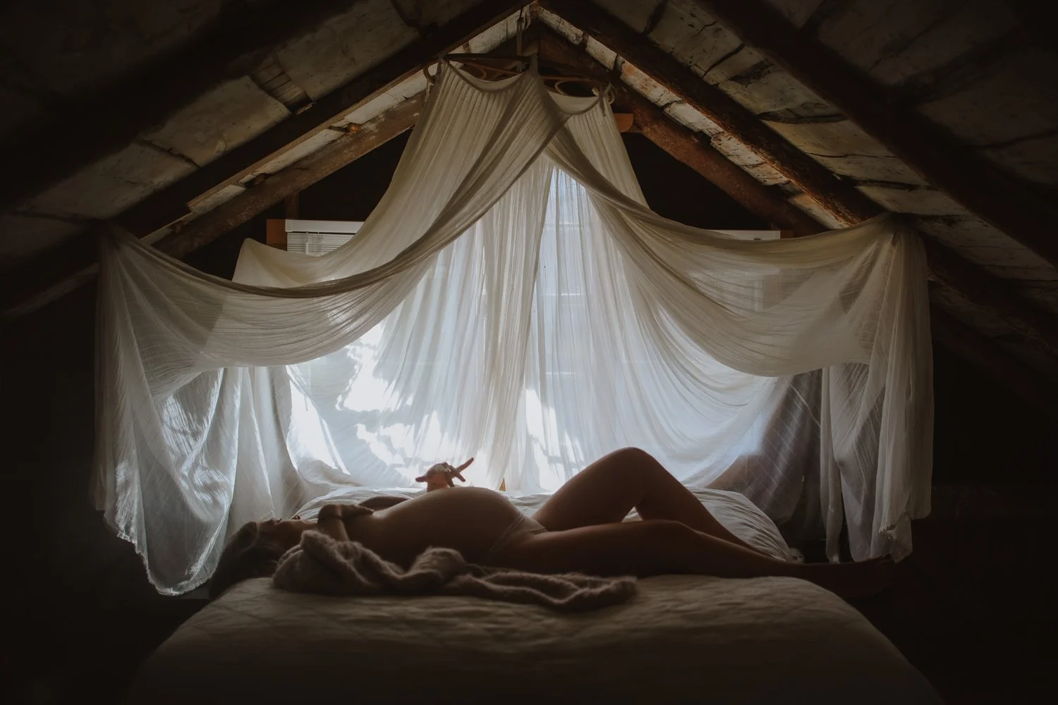 woman laying on her back on a bed draped in white curtains.