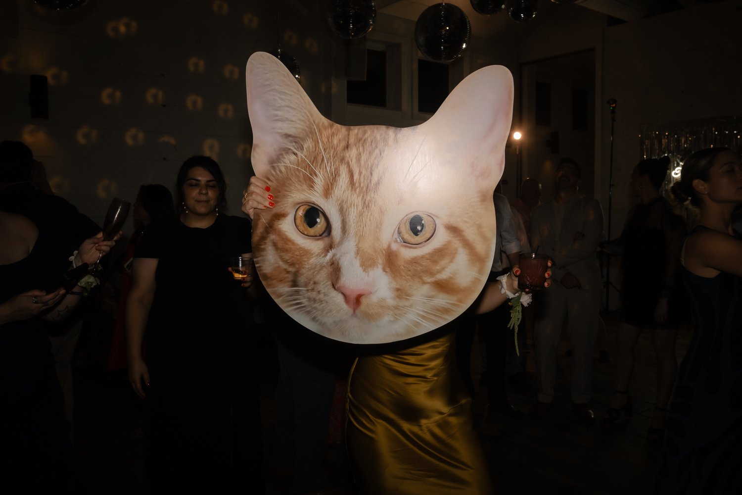 Guest dances with large cat print during wedding reception.