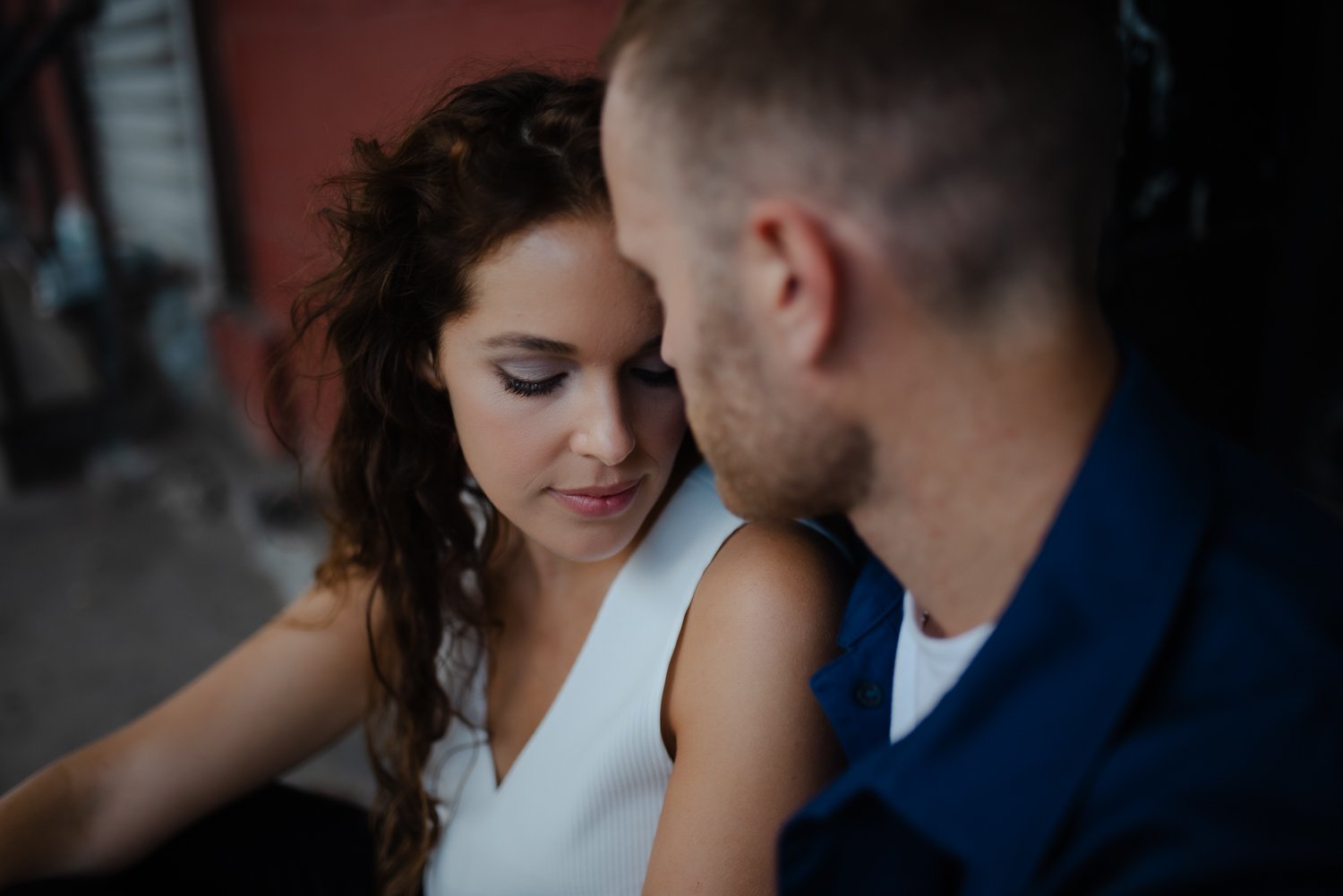 A young woman and a man with their foreheads touching, eyes closed, sharing an intimate moment.