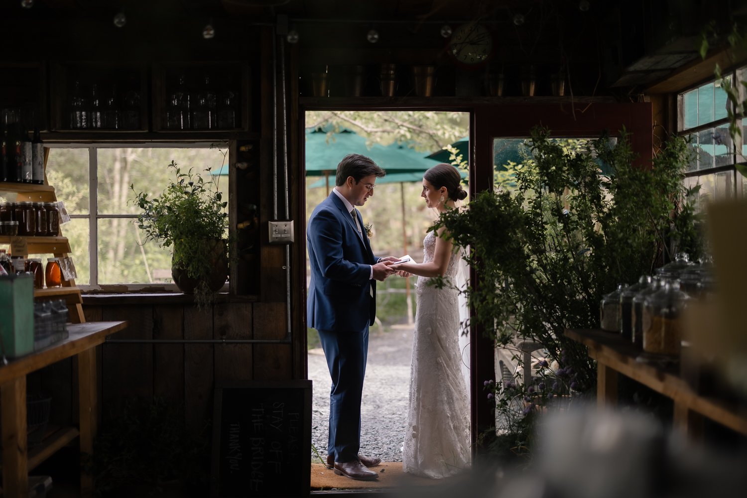Groom reads his vows to his bride in private moment shot through a building doorway.