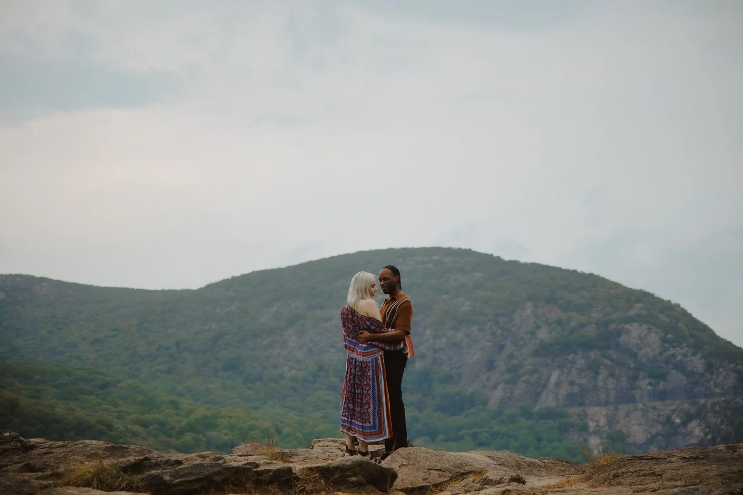 Couple hugs on a mountain top overlooking the Catskills Mountains in New York.