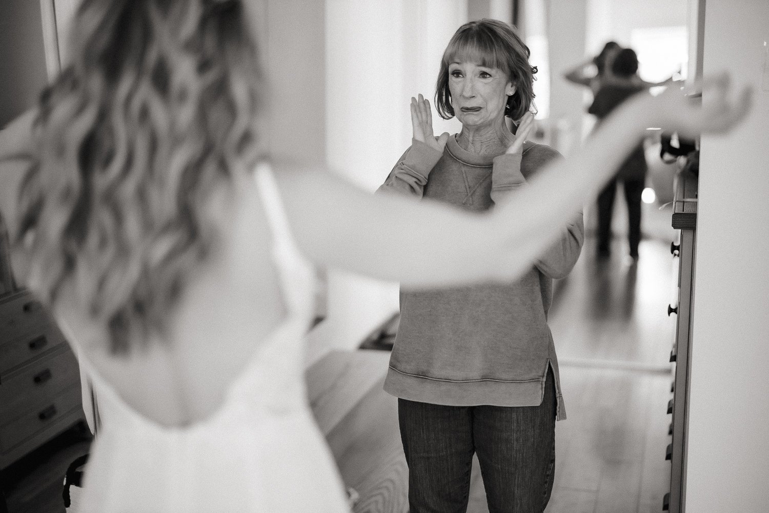 Bride reaching toward her mother in an emotional black and white candid moment.