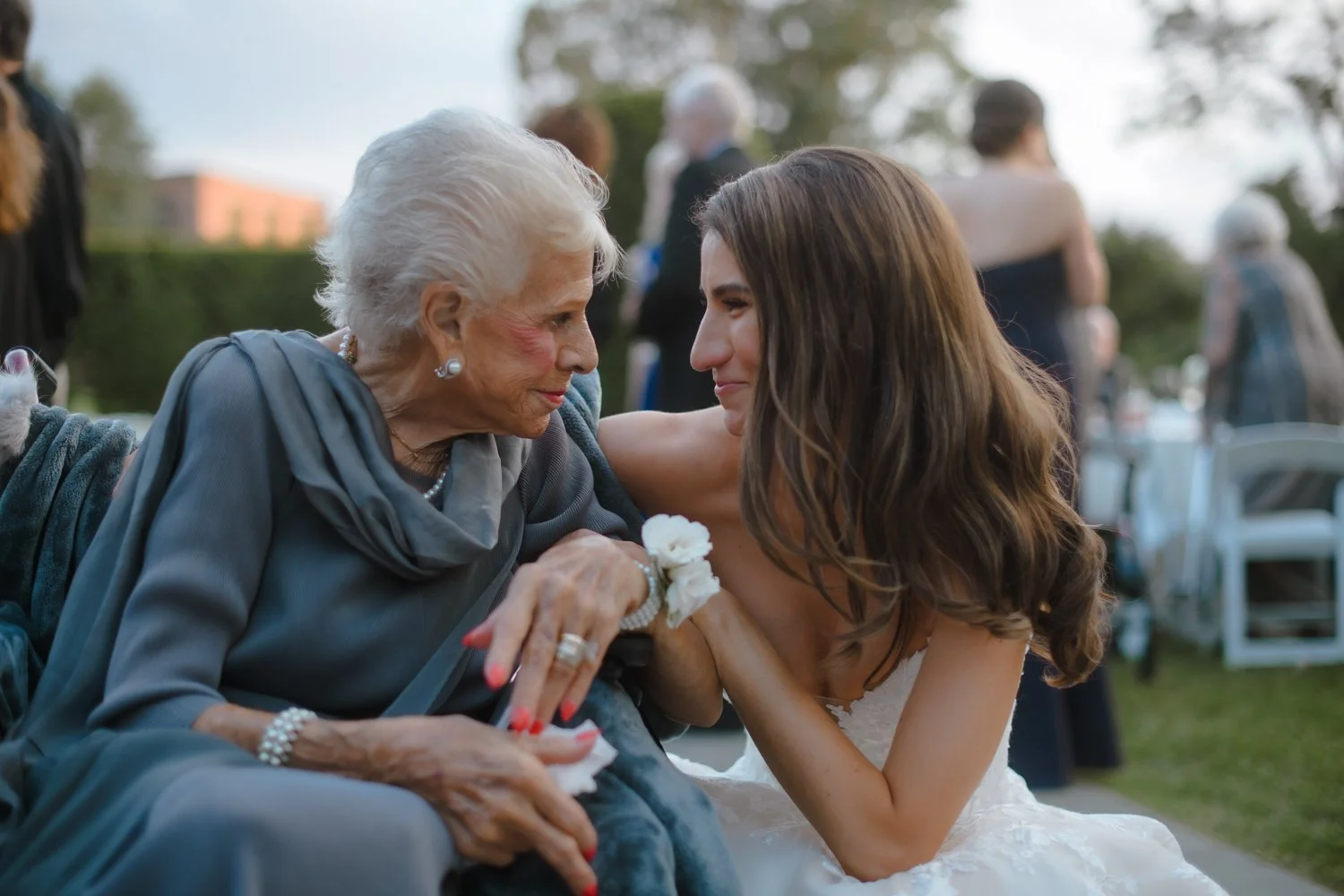 Bride sharing a tender moment with her grandmother at an outdoor wedding reception.