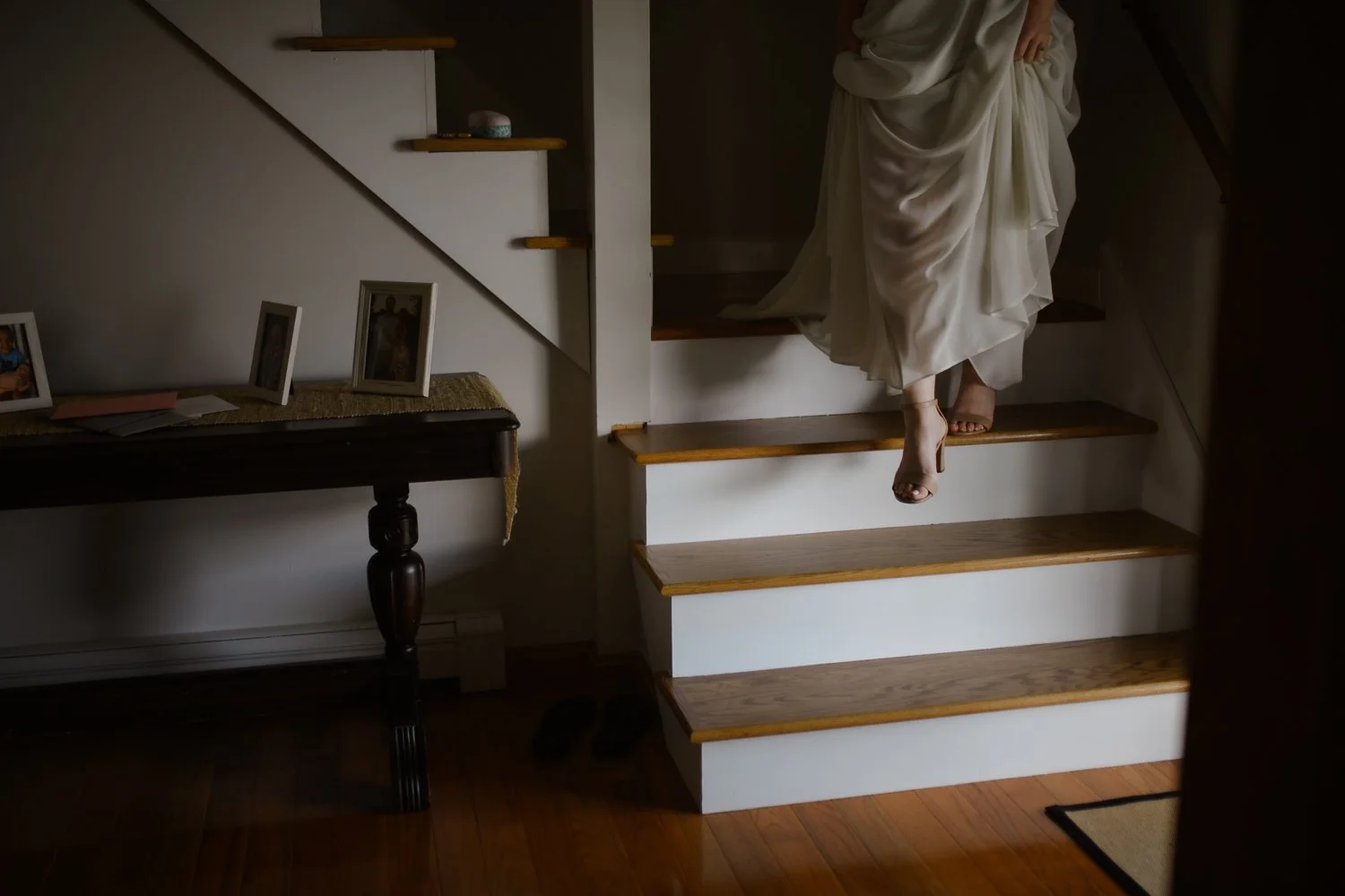 Person in a flowing dress walking down a staircase, partially visible from the waist down.