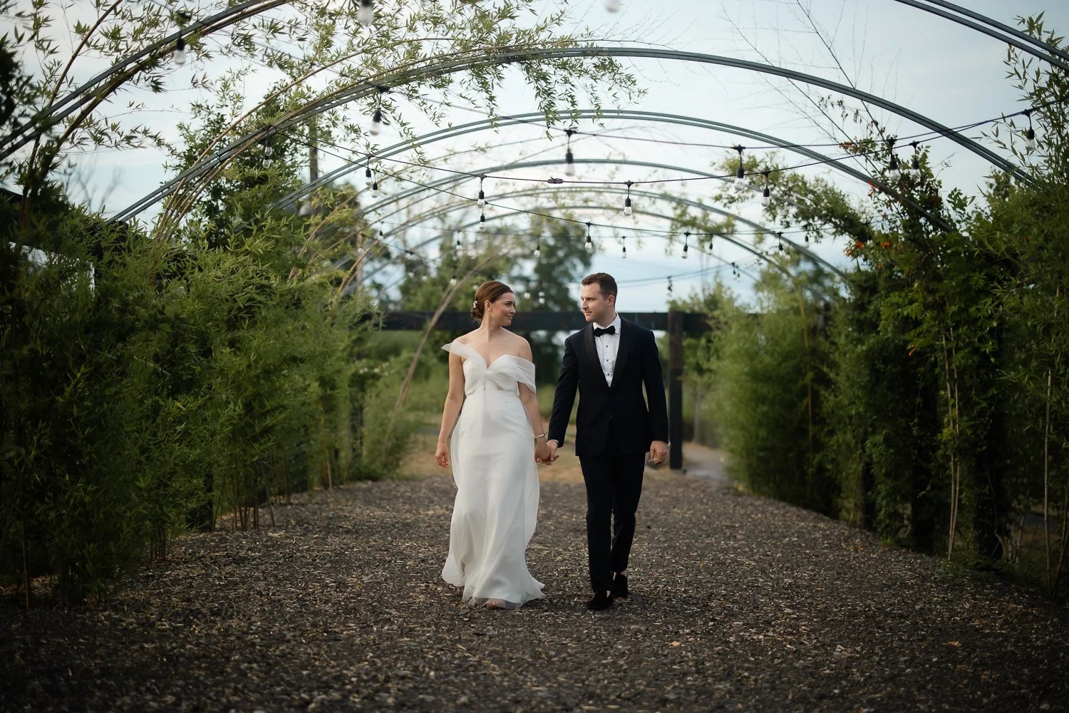 Bride and groom hold hands walking under a geometrical awning on their NY wedding day.