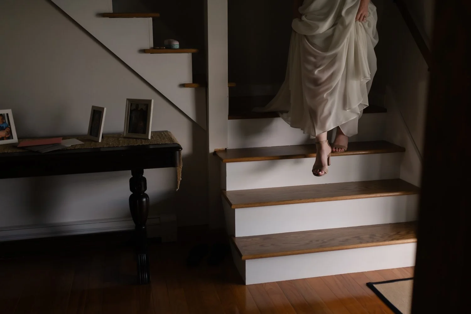 Soft light hits brides foot as she walks down the stairs.