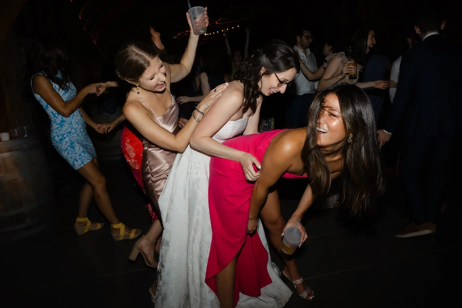 Bride laughs and dances with her friends at her wedding reception.