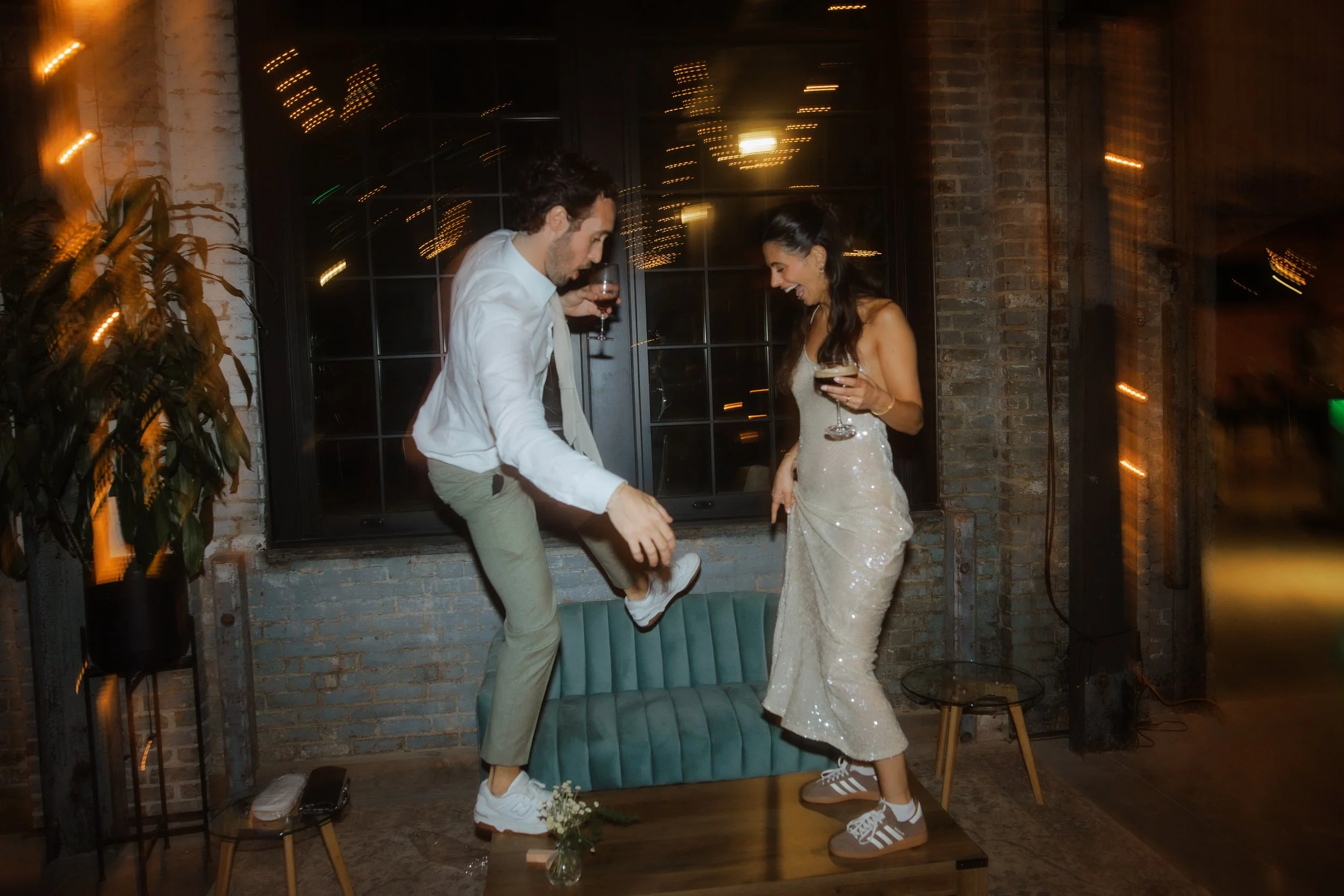 Bride and groom laughing together on a lantern-lit patio during their Hudson, NY wedding reception.