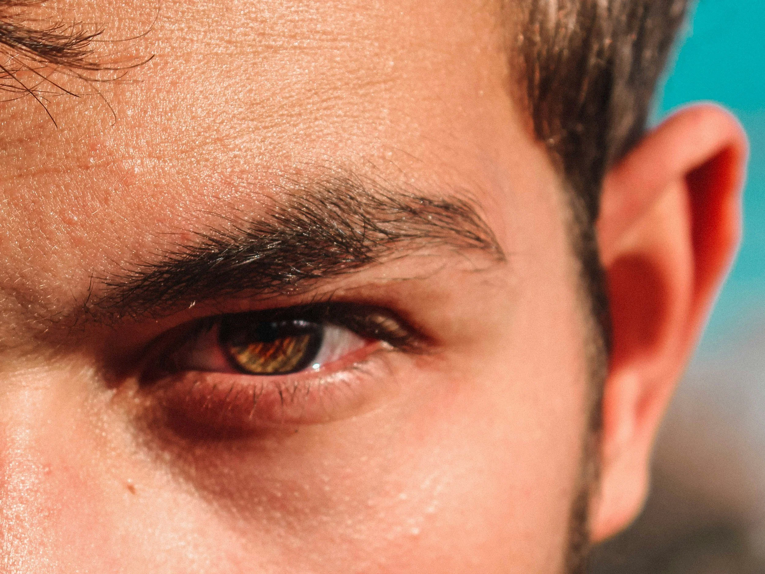 Close-up of a person's eye, eyebrow, and part of the face with detailed skin texture.