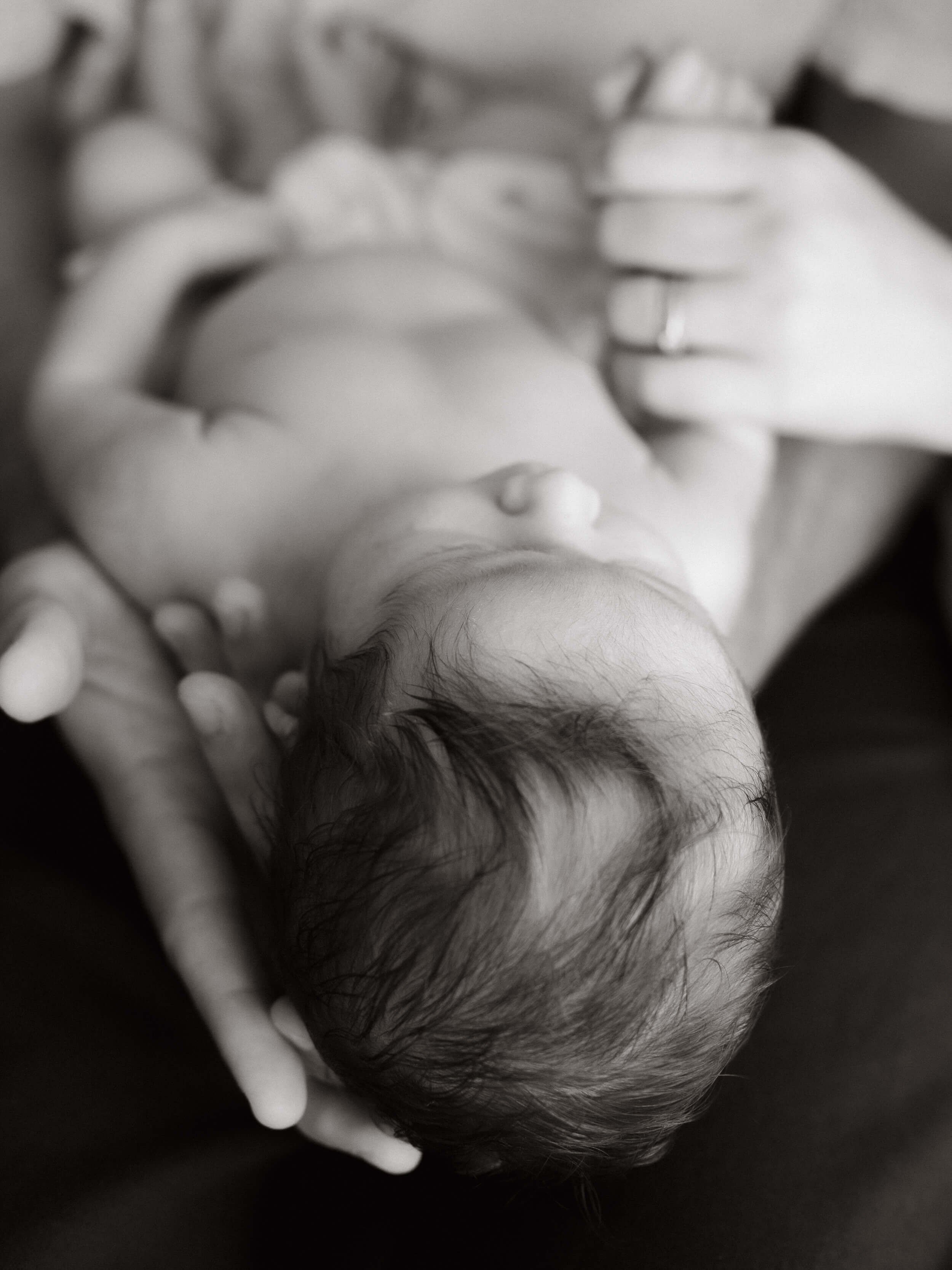 Crno-bijela slika bebe kako leži tati u ruci