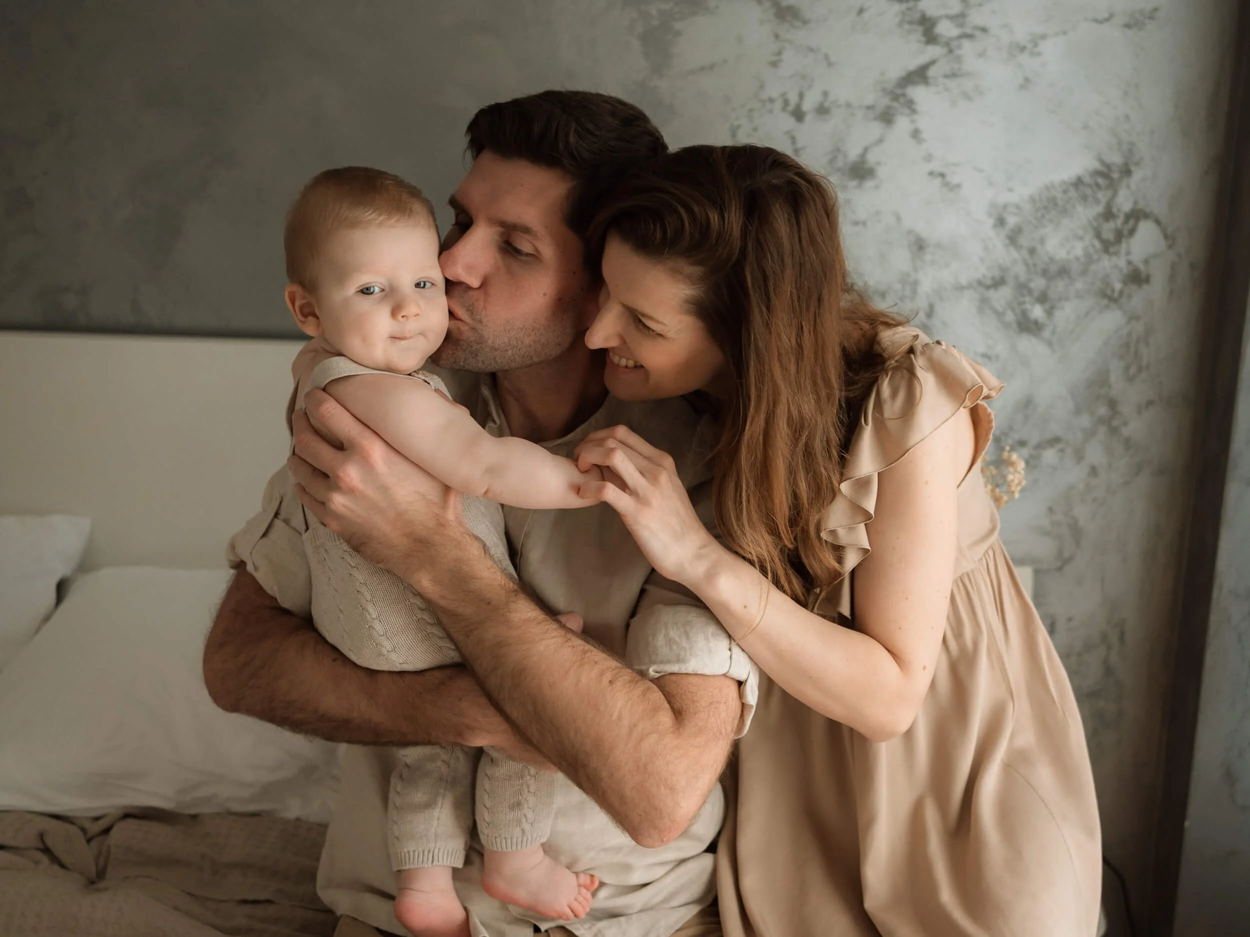 Beba u naručju roditelja, tata ljubi bebu