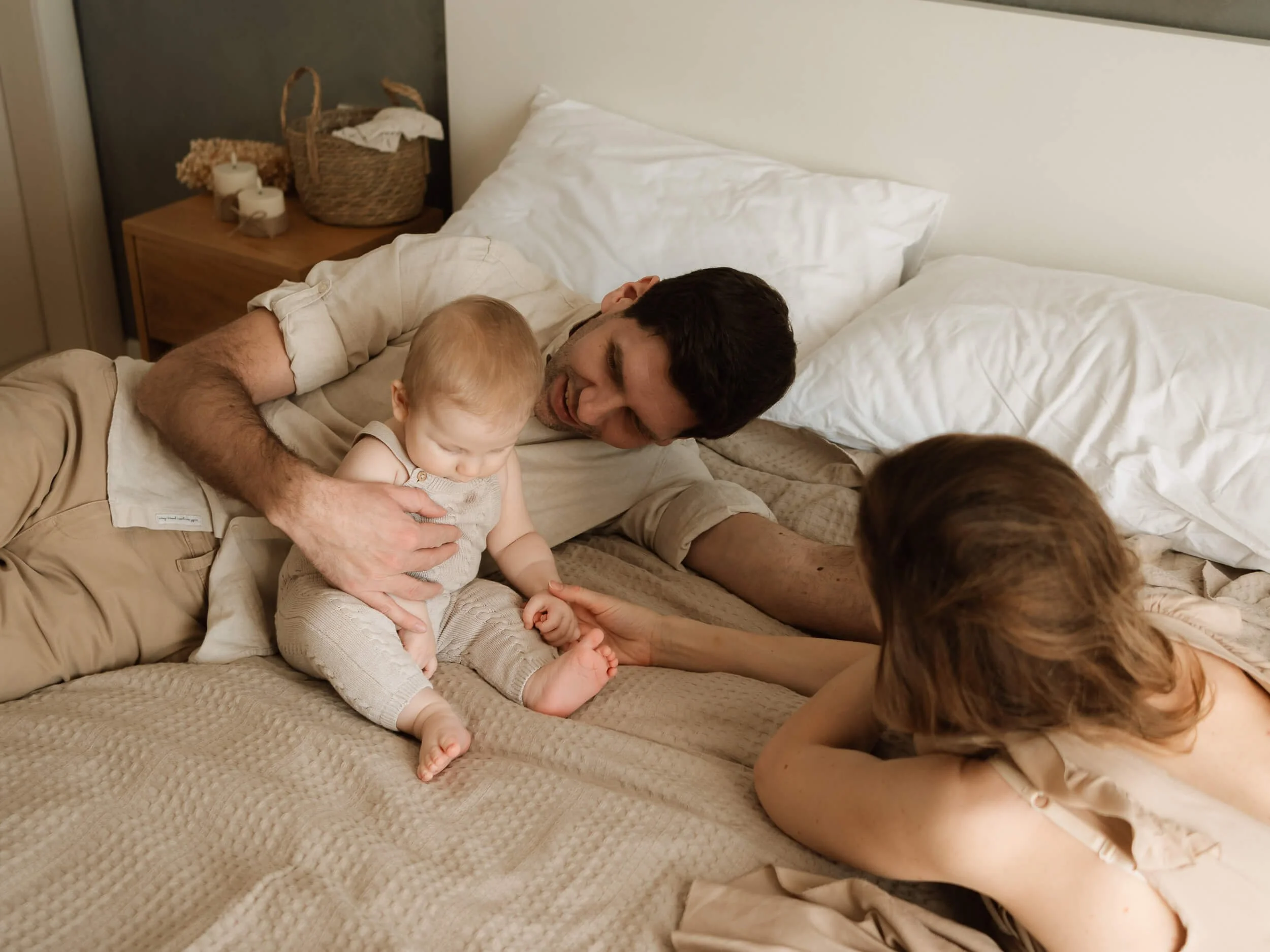 Roditelji se igraju sa bebom kod kuće na krevetu