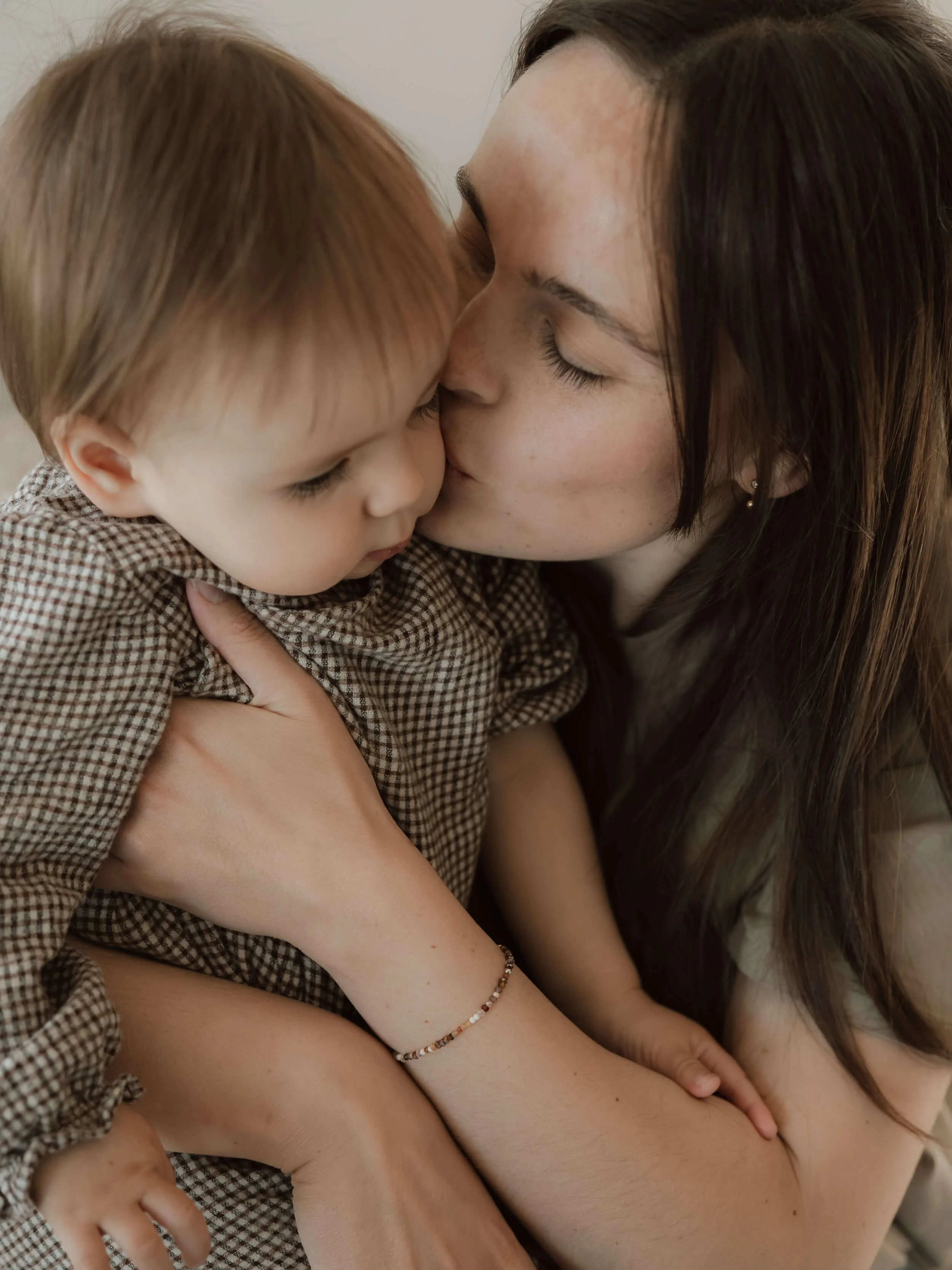 Mama ljubi malenu kći tijekom obiteljskog slikanja u njihovom domu