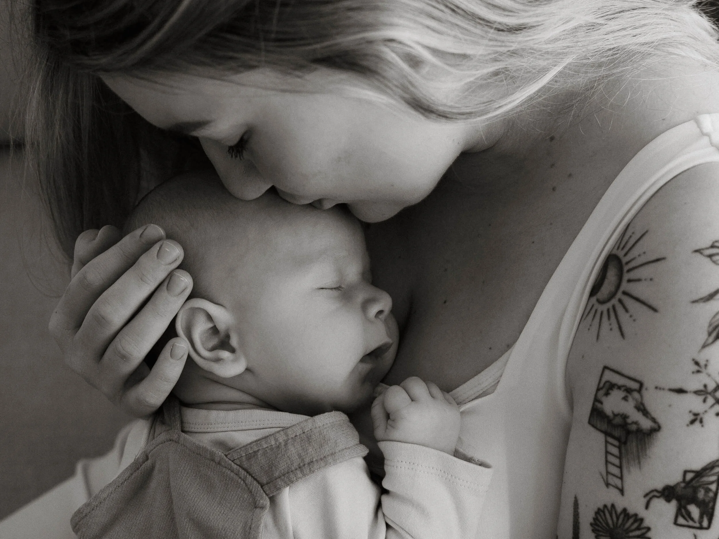 Crno-bijela fotografija majke kako ljubi bebu